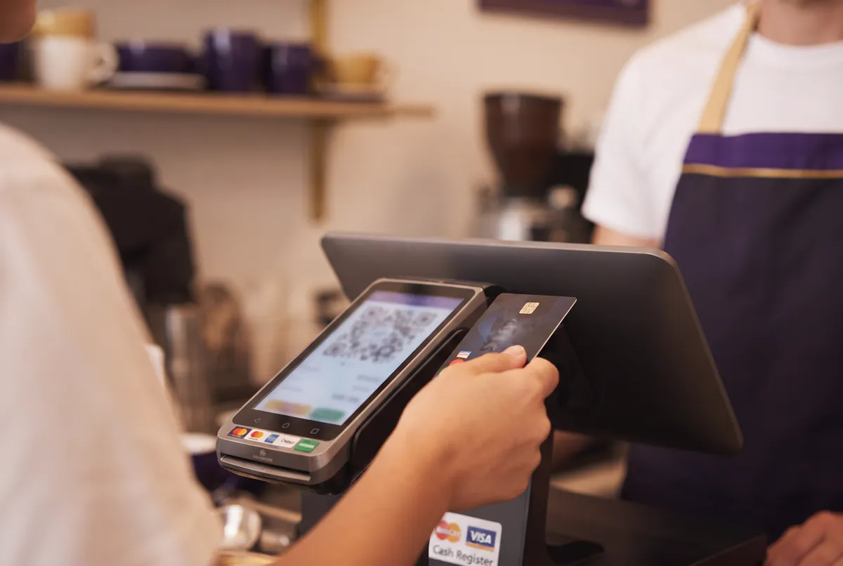 A customer making a contactless card payment at a small Australian cafe with a clearly visible total but no readable text
