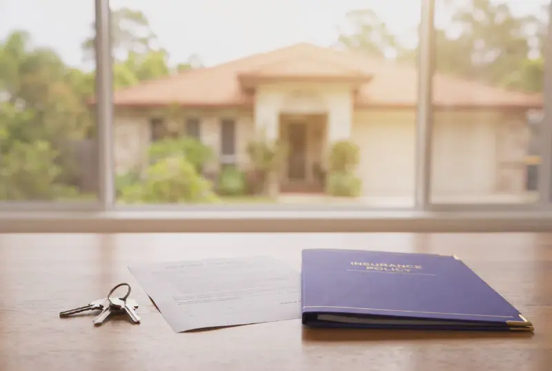 A Queensland house with a sale contract, keys and home insurance policy on a desk